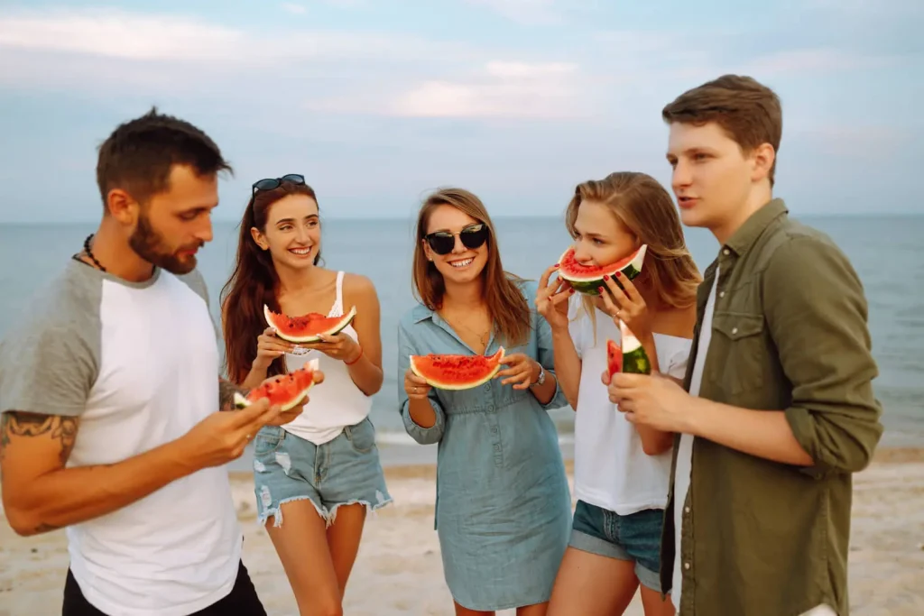 Gruppo di giovani con anguria in spiaggia