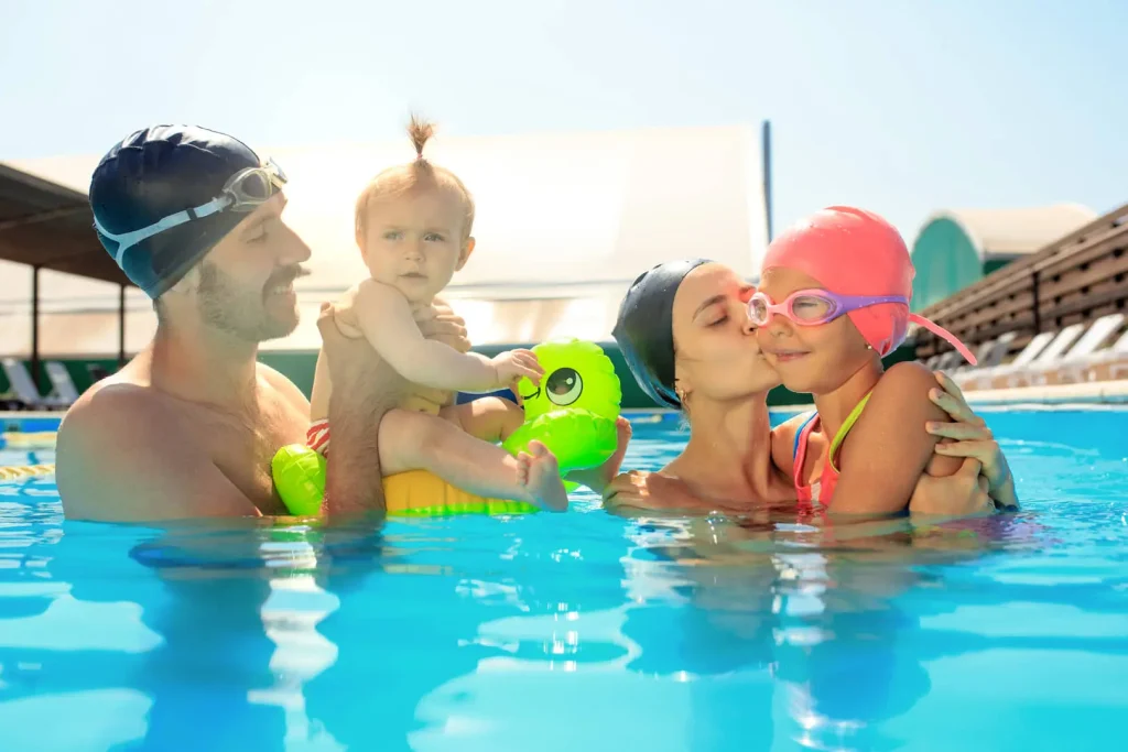 Famiglia in piscina con bambino e neonata